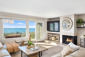 Spacious living room with ocean views, a fireplace and plenty of comfy seating.