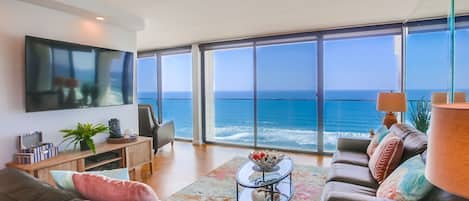 Living room with large TV, great for relaxing or entertaining with stunning ocean and beach views!