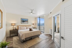 Spacious king bedroom with ceiling fan, desk, balcony, and soft bedside lights
