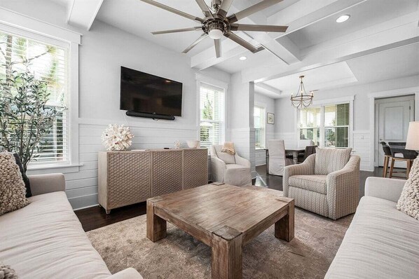Bright and airy living area designed for comfort, offering ample seating, a large TV, and stylish finishes.