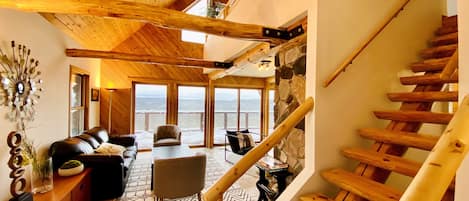 Main level- living area with walkout deck and stairs going up to the loft