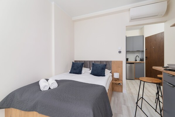 A modern bedroom with a comfortable double bed, gray bedding, and wooden accents.
