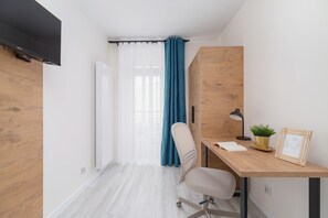 A workspace by the window with a wooden desk, chair, and decorative touches.
