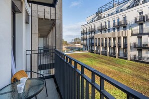 A balcony with outdoor seating, overlooking a contemporary residential complex.
