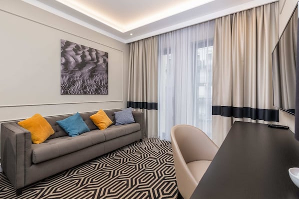 A stylish living area featuring a gray sofa, bright yellow cushions, and elegant curtains.