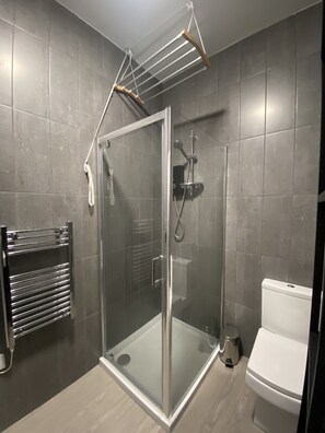 Shower with drying rack above and heated towel rail.