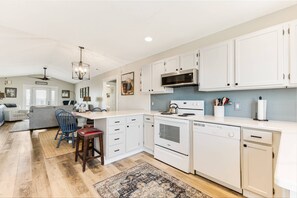 Create a harmonious atmosphere in this kitchen and living room area, with pristine white cabinets and a stylish stove that elevate the overall.