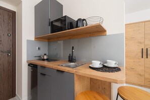 A compact kitchenette with wooden counters, cabinets, and basic appliances.
