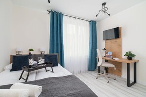 A bright bedroom with teal curtains, a cozy bed, and minimalist decor.
