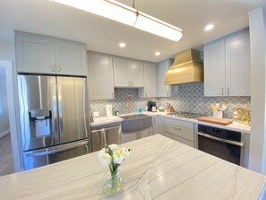 Stainless steel kitchen with gas cooktop, oven, dishwasher and double fridge.