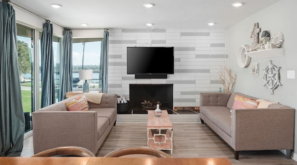 This bright and modern living space features contemporary furniture, a smart tv, and a fireplace.