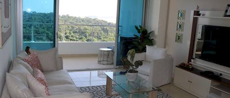 View of ocean, jungle from living room, floor-to-ceiling glass and private balcony.
