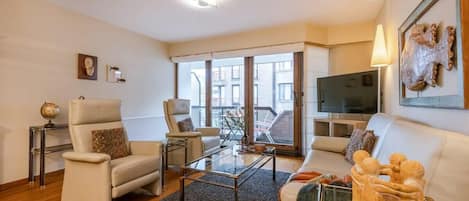 Spacious livingroom with TV and terrace next to it.