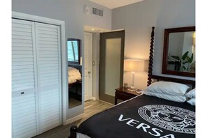 Bedroom with queen size bed, TV, and large hanging closet.