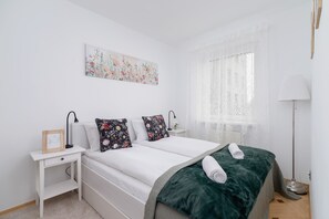 A cozy bedroom with a comfortable bed, green blanket, and soft decor.
