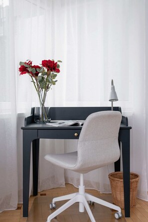 A small work desk by the window with a modern chair and fresh flowers.
