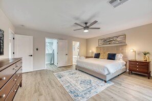 Primary bedroom with a king size bed, a desk and it's own smart television.