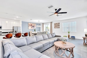 Expansive Open Living Area With A Plush Sectional Sofa Stylish Coffee Table And Seamless Access To Dining And Kitchen Spaces