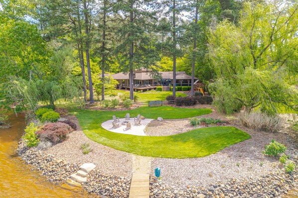 Stunning fenced back yard, fire pit, and stone steps leading into the lake