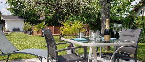 Terrasse privative avec table, chaises, transats, parasol, barbecue. 