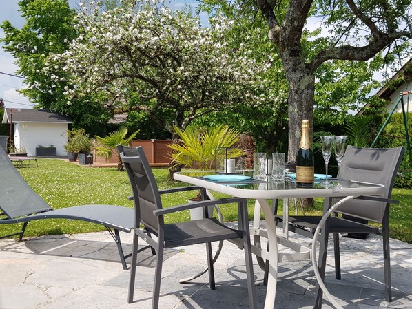 Terrasse privative avec table, chaises, transats, parasol, barbecue. 