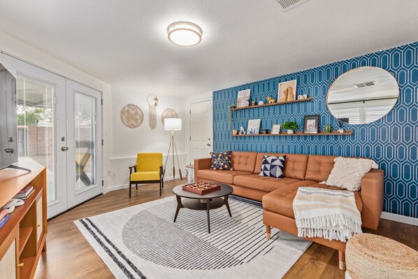 Instagrammable living room with large couch, chair, 58" TV. French doors to yard