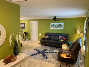 Spacious living room with TV and comfortable reclining sofas.