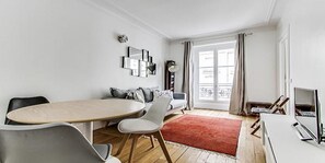 Bright and warm living room with grey sofa stylish lamp and dining for three