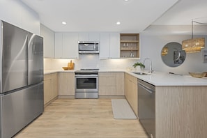 Fully equipped kitchen with quartz countertops and undercabinet lighting.