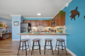 Fully equipped kitchen with full-size appliances, and dining area with 4 bar stools.