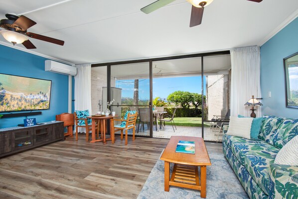 Living room with split AC, ceiling fan, and smart TV
