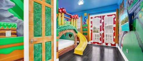 This themed room boasts a playful slide from the bed to the floor, adorned with a burst of vibrant colors.