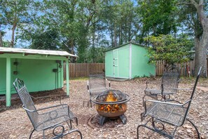 In the Natural Area of the Backyard, Enjoy the Fire Pit anytime of year. The Storage Shed to the Right has the Beach Toys & Bikes.