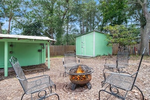 In the Natural Area of the Backyard, Enjoy the Fire Pit anytime of year. The Storage Shed to the Right has the Beach Toys & Bikes.
