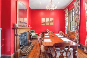 The banquet-sized dining room features an 8-seat timber table and a cosy gas fireplace set underneath an antique candelabra.