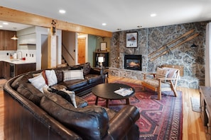 Living Room- Relax next to the warm fireplace after a long day of skiing! - Photo of living room showing the leather couch, round coffee table, end table, wooden armchair and gas fireplace.