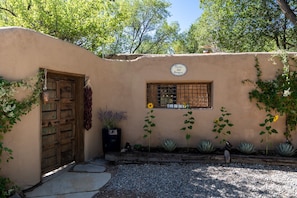 An adobe house with a door and plants.