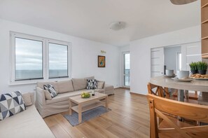 A bright and cozy living room with a comfortable sofa, wooden furniture, and large windows.
