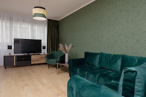 A cozy living area featuring a green sofa, a stylish lamp, and a workspace.
