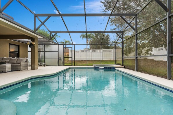 Spacious pool area with screened enclosure, perfect for relaxing or hosting outdoor gatherings.