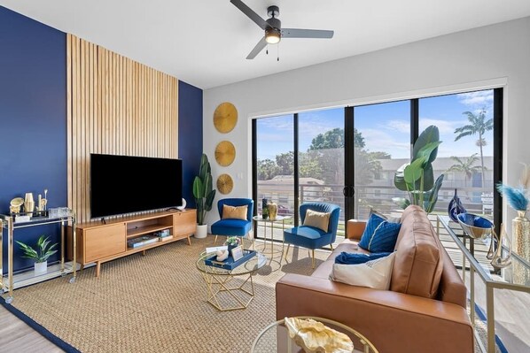 [Living Room] - wraparound balcony w/ views, genuine leather couch, velvet accent chairs, 65" TV w/ complimentary Netflix, board games, bar cart, blankets, custom accent wall