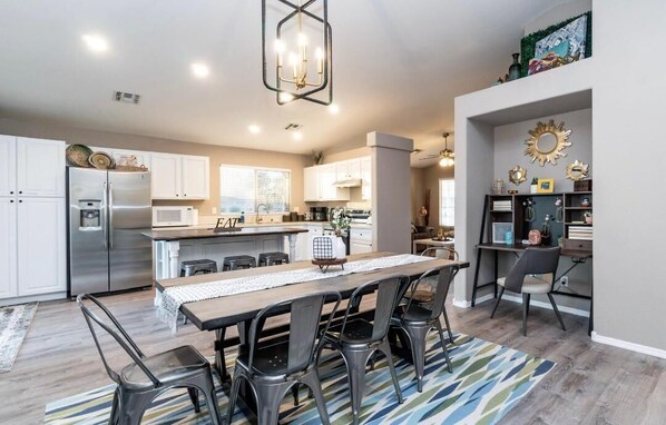 Dining room that flows into the kitchen area has a 55" Roku TV and work desk.