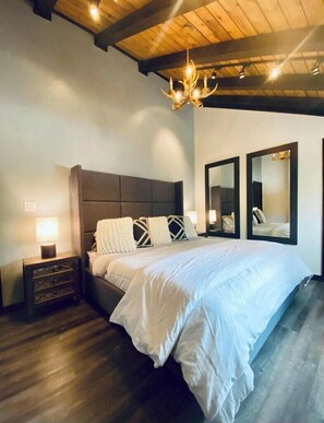 Relax in the serene master bedroom with luxurious bedding, soft lighting, and a rustic chandelier. The vaulted ceiling and tasteful decor make this a perfect sanctuary for rest and rejuvenation after a day of adventure.