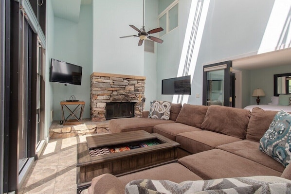 Imagine gathering around this cozy fireplace in the living room, with natural light pouring in from the high windows. The sectional sofa invites you to sink in and enjoy a movie or a good book, making this space perfect for relaxation.