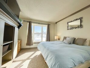 Drift into a peaceful slumber in this spacious bedroom featuring a luxurious Queen bed. The large window frames stunning views, providing a serene backdrop. You'll appreciate the tasteful decor and abundance of natural light. (Bedroom #2)