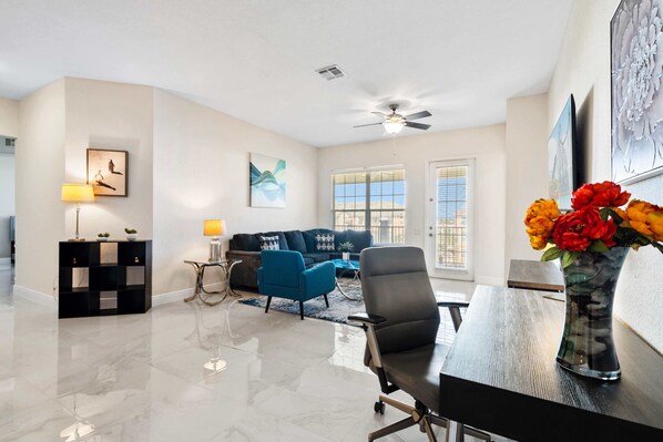 Living area with a large sofa, smart tv and ceiling fan