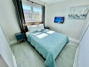 Master bedroom with queen bed and smart TV.