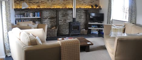 Cosy lounge, tastefully finished in natural fabrics, with log burning stove.
