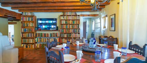 A dining table with plates and glasses in a room with bookshelves.