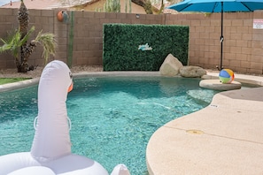 Swimming pool with inflatable toys and photo backdrop.